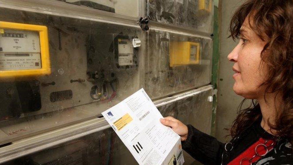 Una mujer consulta una factura de la luz junto a un contador.-ÁLVARO MONGE