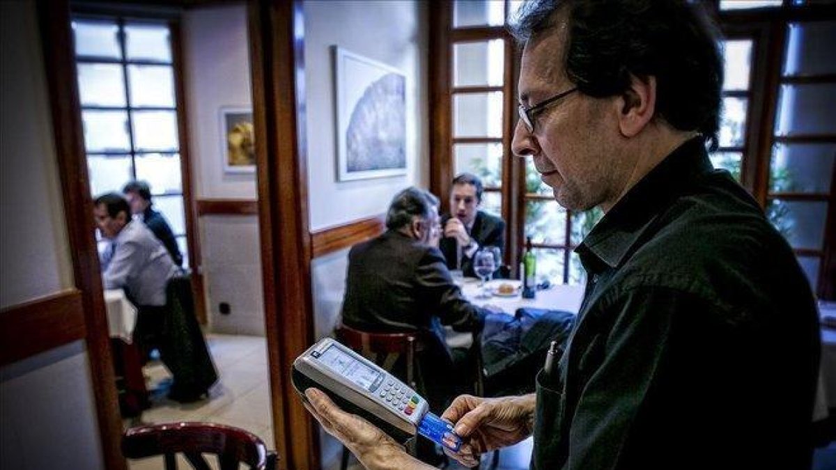 Un camarero cobra una cuenta en un restaurante.-JOAN CORTADELLAS