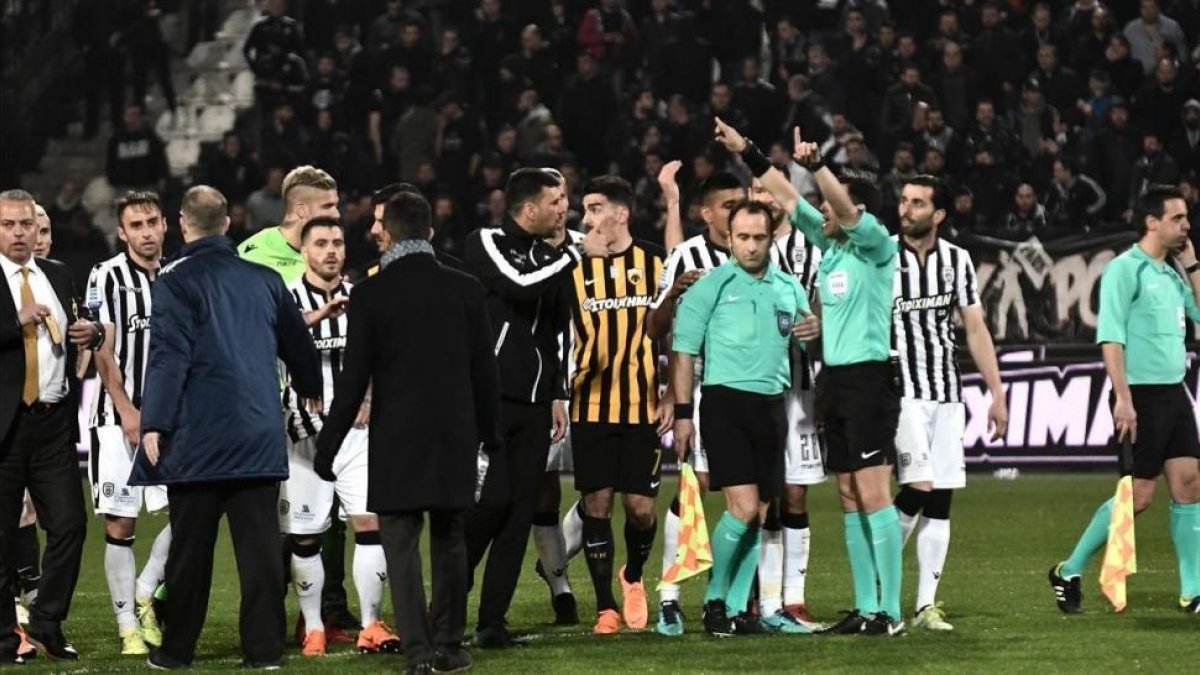 Árbitros y jugadores, durante los incidentes en el tramo final del partido en campo del PAOK.-/ AFP / SAKIS MITROLIDIS