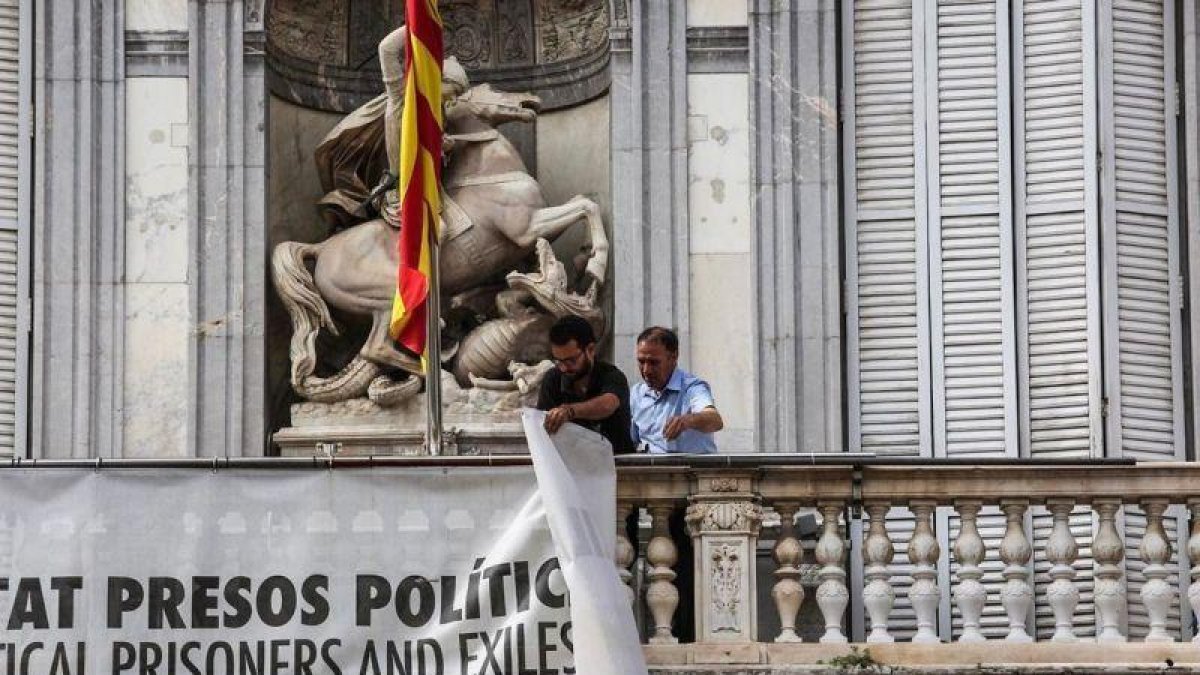 Dos trabajadores de la Generalitat retiran la pancarta que colgaba del Palau.-ÁNGEL GARCÍA