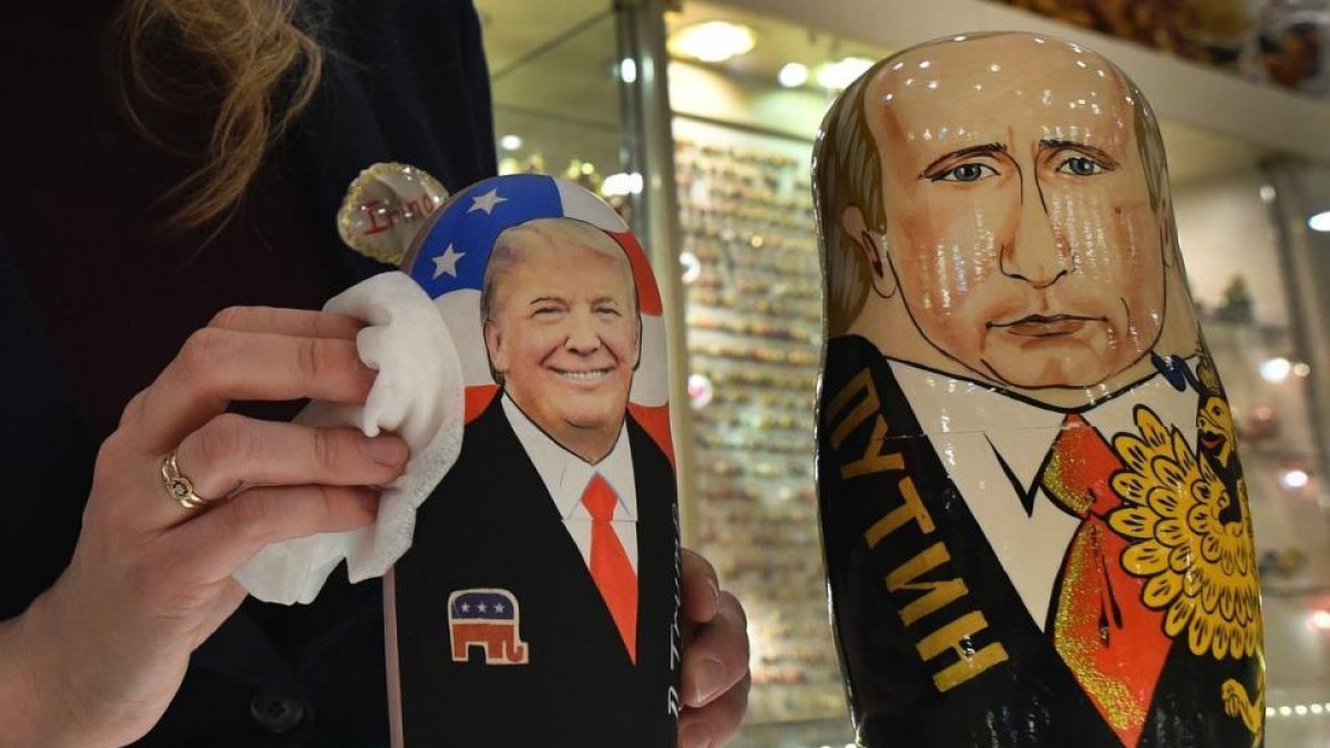 La empleada de una tienda de 'souvenirs' de Moscú saca brillo a las matrioskas de Trump y Putin, a cuatro días de la investidura del primero como presidente de EEUU.-AFP