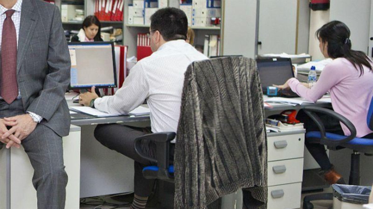 Mujeres y hombres en una oficina.-ARCHIVO