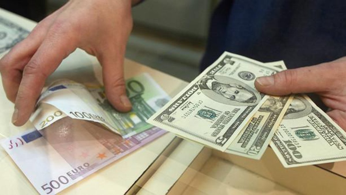 Euros y dólares en las manos.-AFP / ARCHIVO