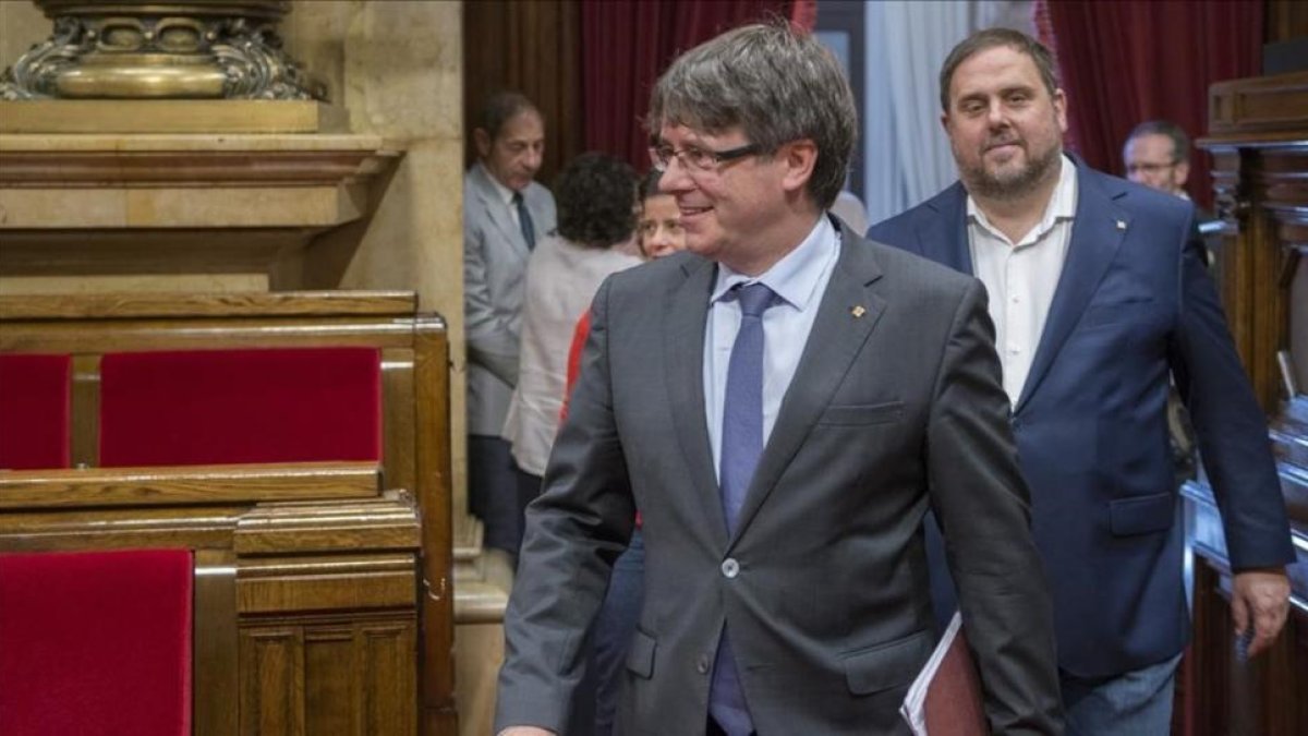 El presidente de la Generalitat, Carles Puigdemont, y el vicepresidente del Govern, Oriol Junqueras, en el hemiciclo del Parlament.-FERRAN SENDRA