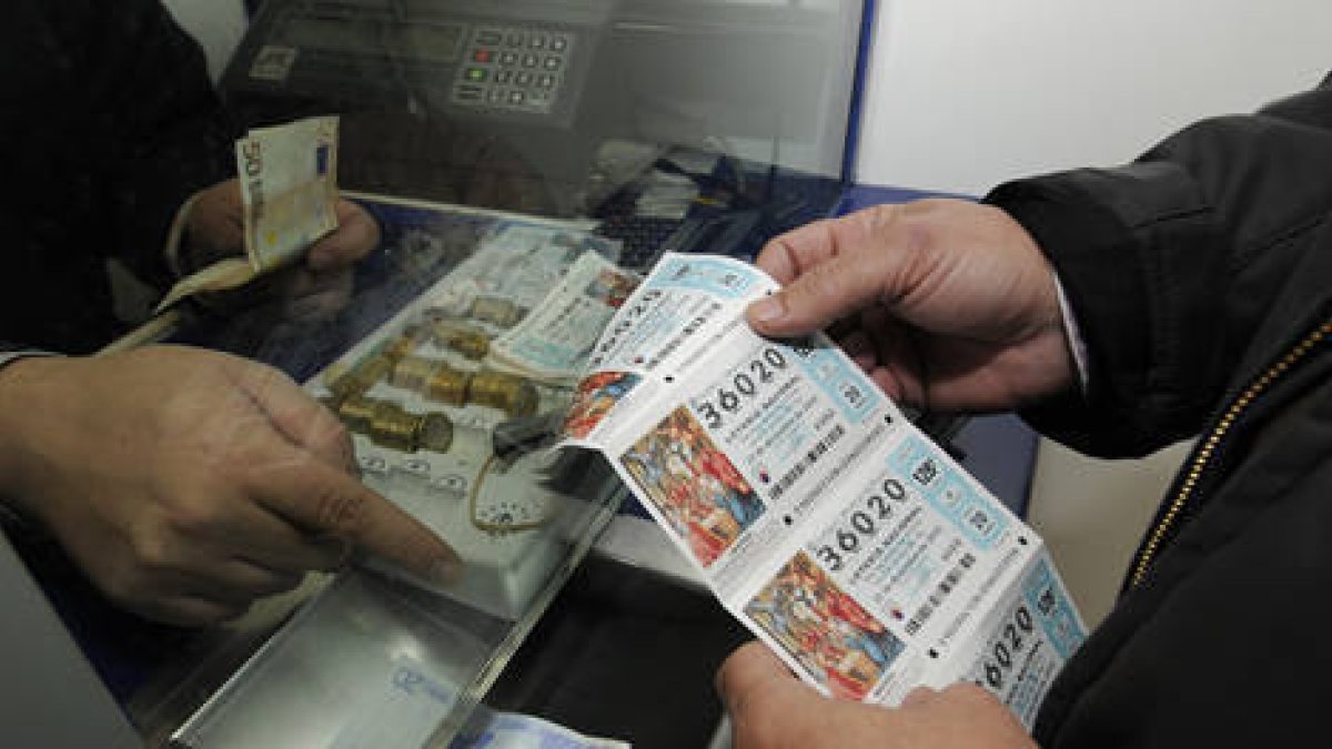 Un hombre compra tres décimos de lotería en una administración de Soria. / VALENTÍN GUISANDE-