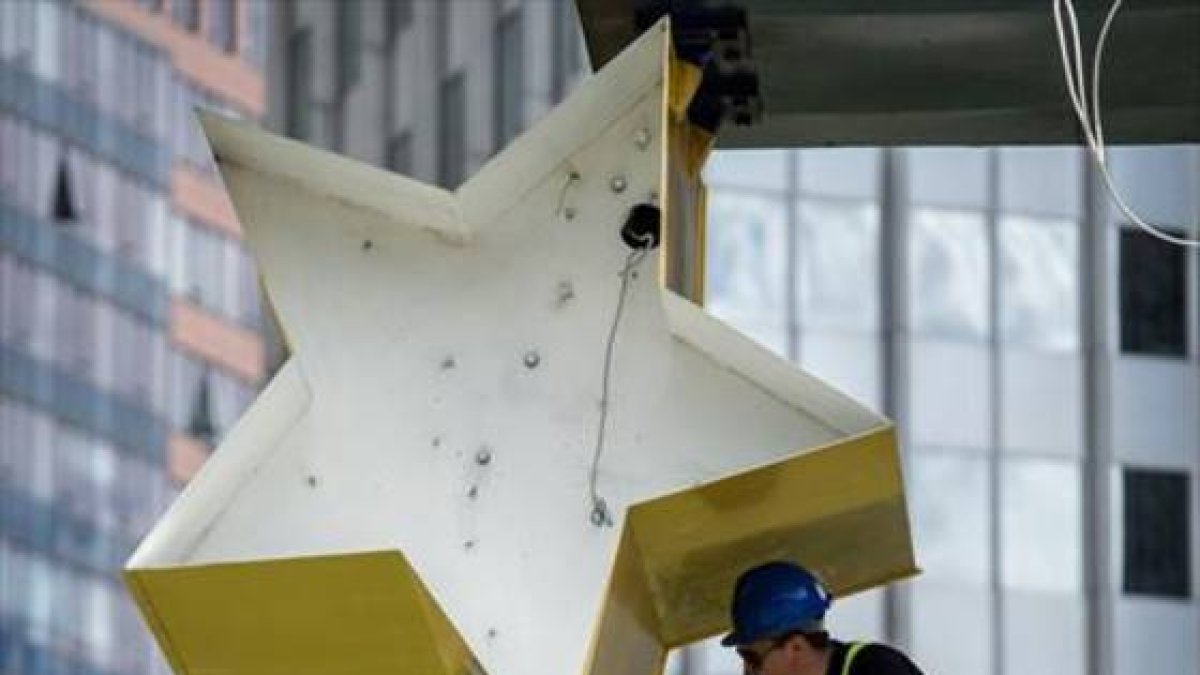 Un operario trabaja en la escultura del logo del euro ante la anterior sede del BCE en Francfort.-AFP / BORIS ROESSLER