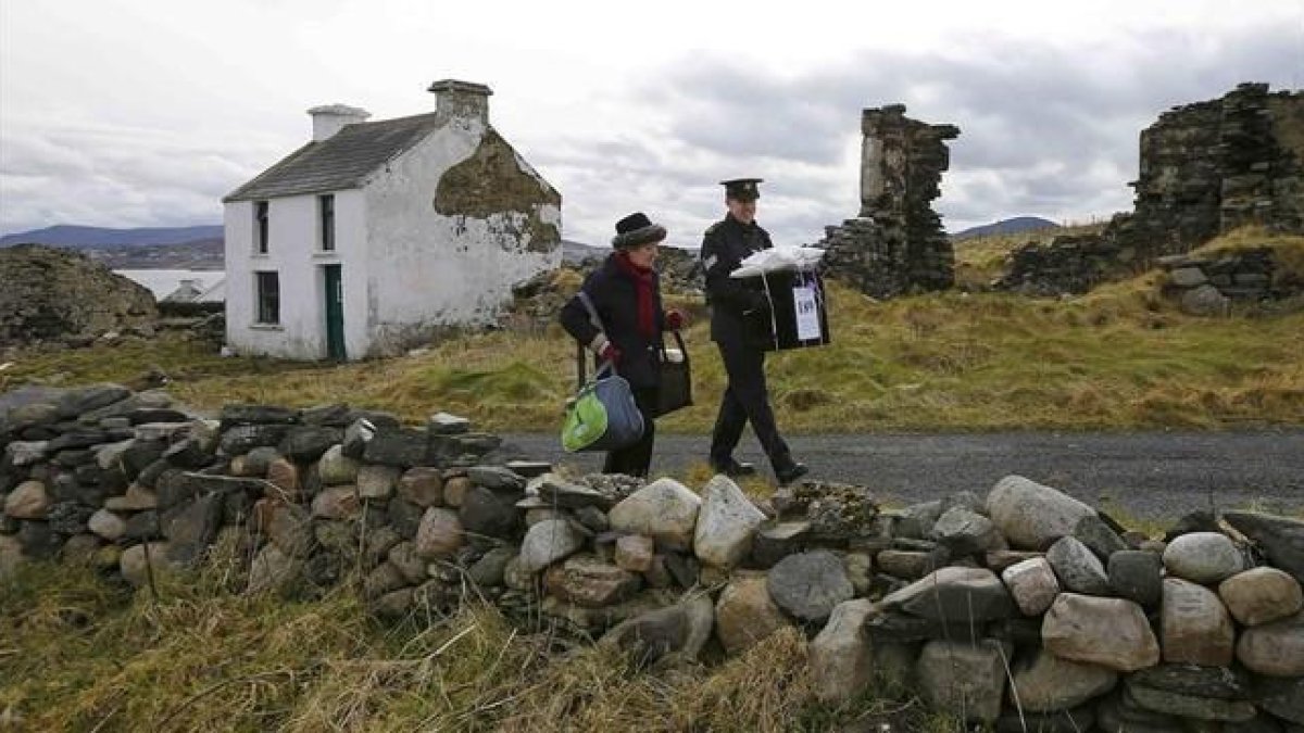 Dos oficiales se llevan la urna de la isla irlandesa de Inishbofin.-REUTERS / DARREN STAPLES