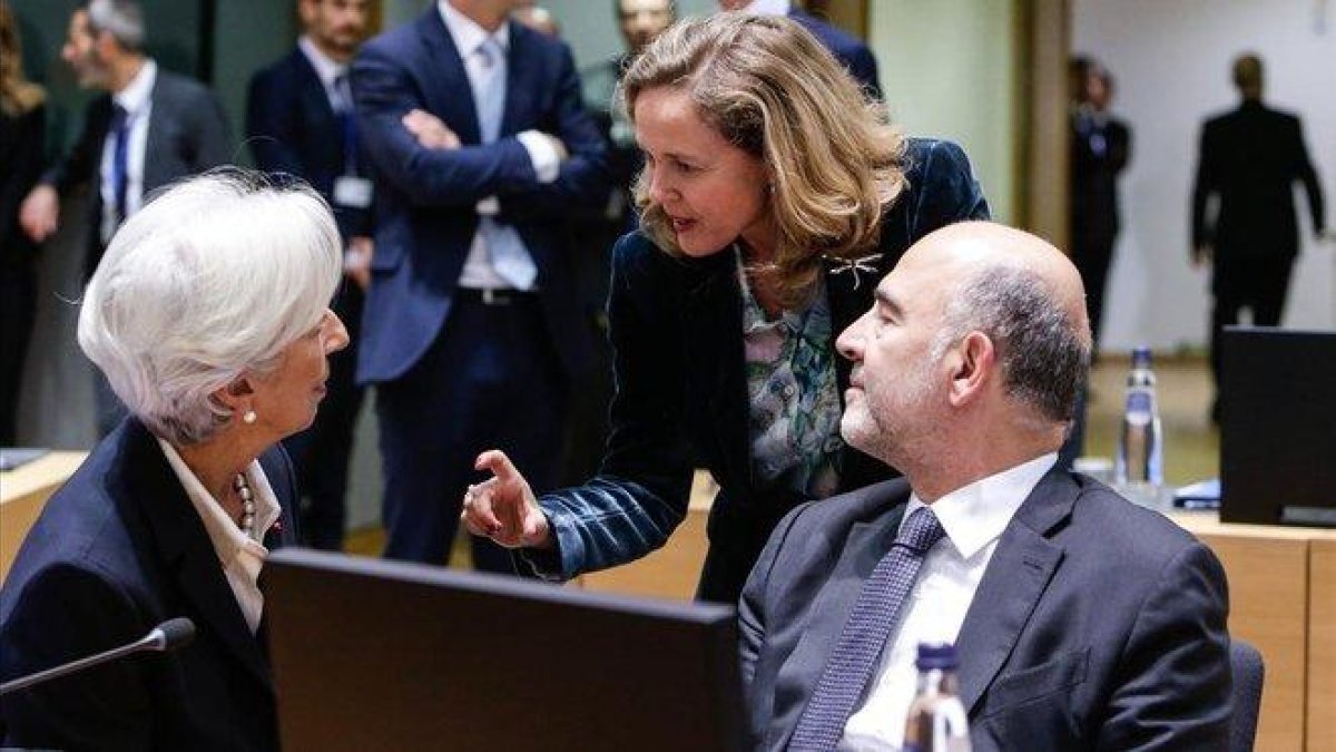 La ministra Nadia Calviño (de pie) conversa con la presidenta del BCE, Christine Lagarde, y el comisario europeo de Asuntos Económicos, Pierre Moscovici, en Bruselas.-AFP / ARIS OIKONOMOU