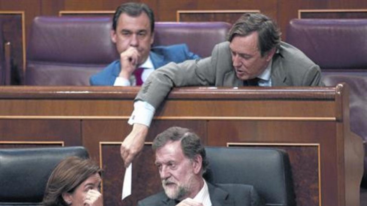 Mariano Rajoy y Soraya Sáenz de Santamaría hablan en el banco azul mientras Rafael Hernando les pasa una nota.-DAVID CASTRO