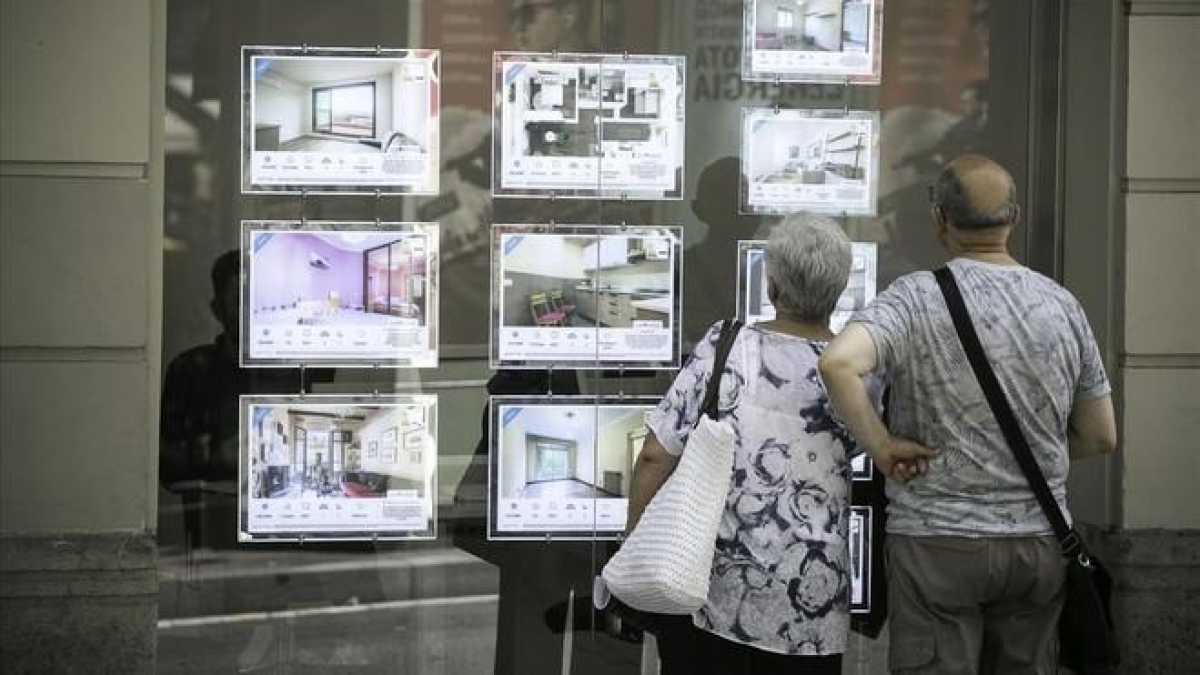 Un pareja consulta la información de una agencia inmobiliaria de Barcelona.-JOAN CORTADELLAS