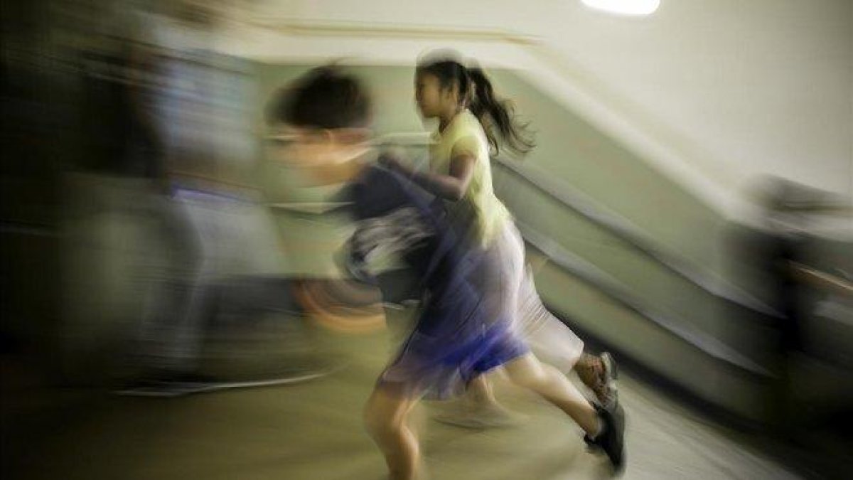 Dos niños corren a la entrada del colegio en Barcelona.-JOAN CORTADELLAS