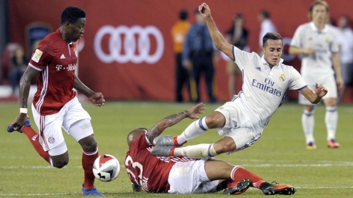 El madridista Lucas Vázquez es derribado por Vidal en presencia de Alaba.-BILL KOSTROUN / AP