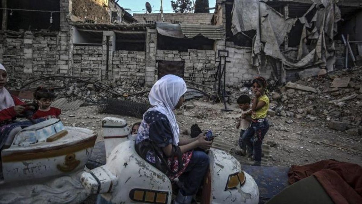 Niños sirios juegan en un carrusel durante el segundo día de la festividad musulmana de Eid Al Adha, en Douma, este martes.-EFE / MOHAMMED BADRA