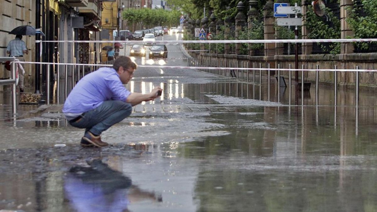 Un hombre fotografía el nivel del agua junto a un extremo cortado de Nicolás Rabal el lunes día 8.-LUIS ÁNGEL TEJEDOR