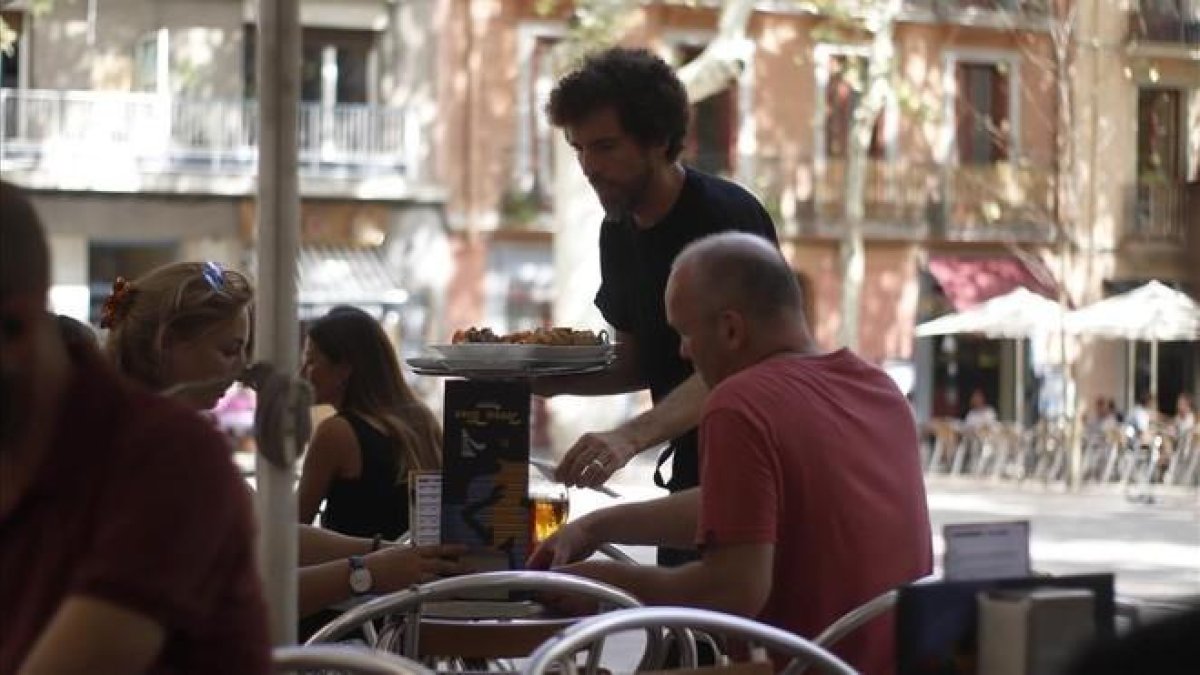 Un camarero atiende a unos clientes.-PAULA GONZÁLEZ