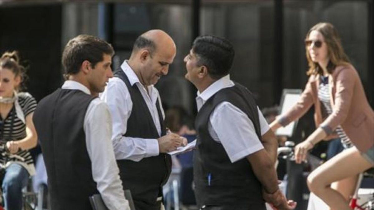 Tres camareros, durante su jornada laboral en un establecimiento de la plaza Reial de Barcelona-JOAN PUIG