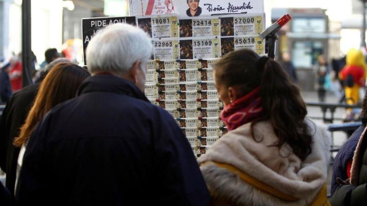 Varias personas adquieren décimos de Lotería de Navidad en los puestos instaldados en la Puerta del Sol (Madrid) este 21 de diciembre-ALVARO SANCHEZ