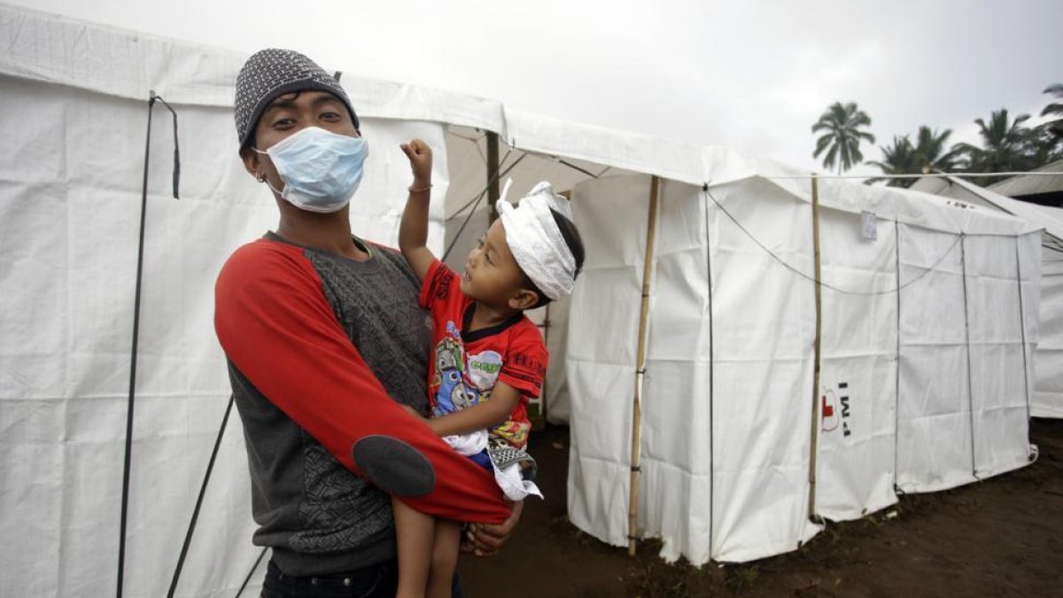 Un padre y su hijo tras ser evacuados a causa de la erupción del volcán Agung.-/ FIRDIA LISNAWATI / AP