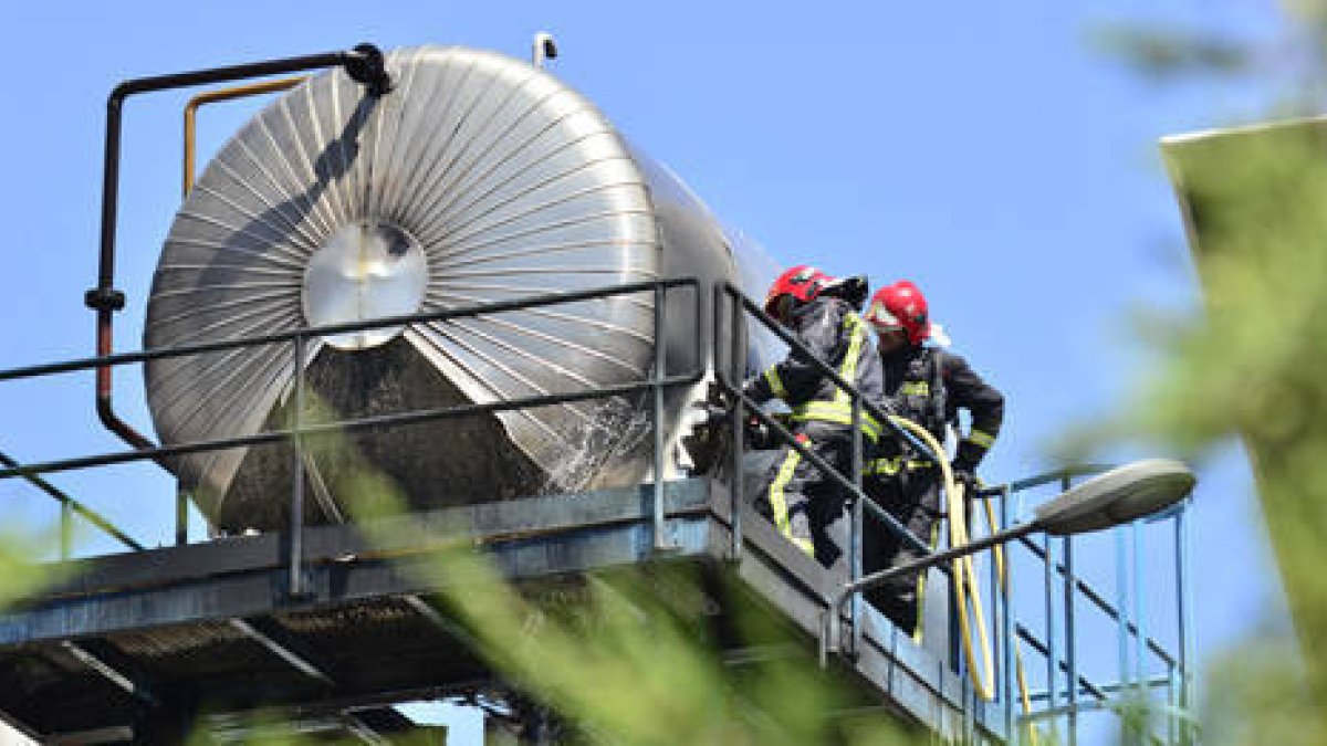 Dos bomberos, ayer, trabajando en las labores de extinción del incendio declarado en la empresa Tableros Losán. / ÁLVARO MARTÍNEZ-