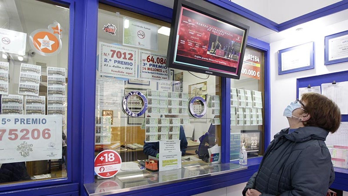 Una persona sigue en directo el sorteo de la Lotería de Navidad en una administración. LUIS ÁNGEL TEJEDOR