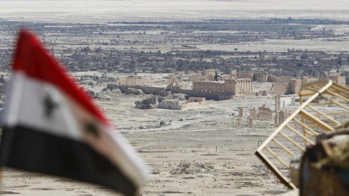Una bandera siria ondea ante las ruinas de la histórica ciudad de Palmira.-REUTERS / OMAR SANADIKI