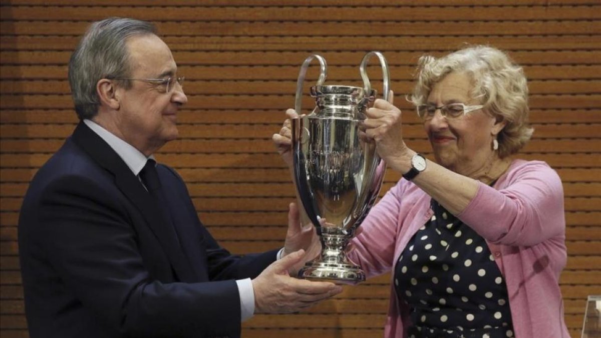 Florentino Pérez le entrega a Manuel Carmena, alcaldesa de Madrid, una réplica de la Champions.-FERNANDO ALVARADO