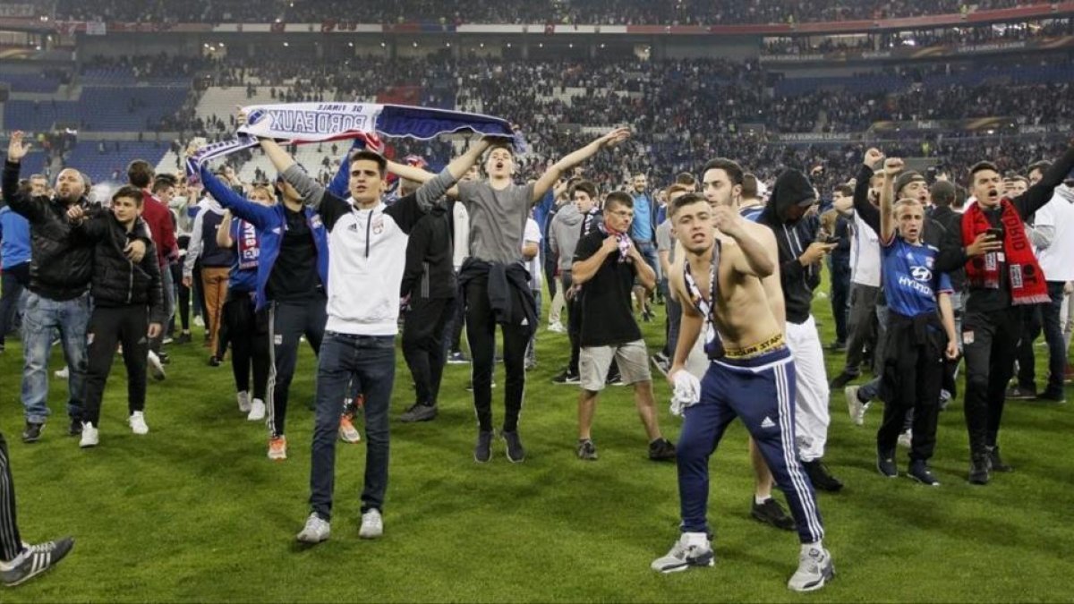 Hinchas del Lyon, durante la invasión del terreno de juego tras los enfrentamientos con la afición del Besiktas.-REUTERS / EMMANUEL FOUDROT