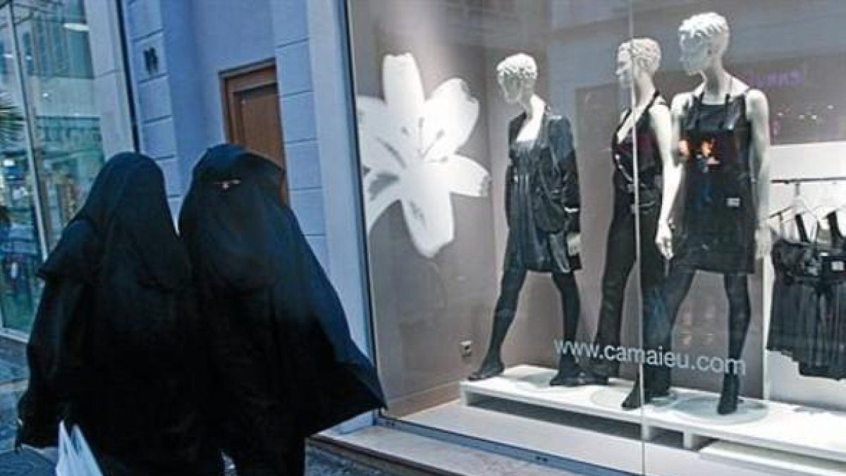 Dos mujeres con velo integral, ante un escaparate de ropa en Marsella.-AP