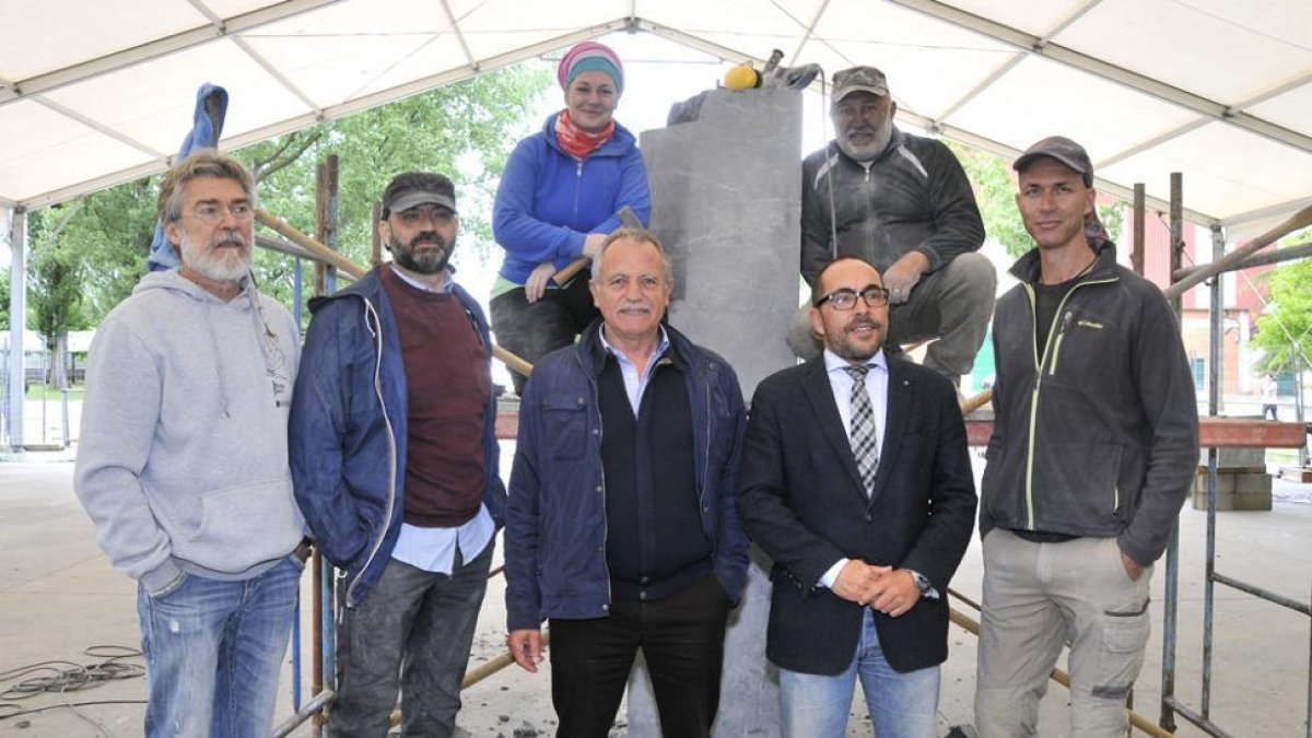 Los escultores posan con algunas de las herramientas que utilizan para dar forma al bloque de mármol negro que deberán modelar.-Valentín Guisande