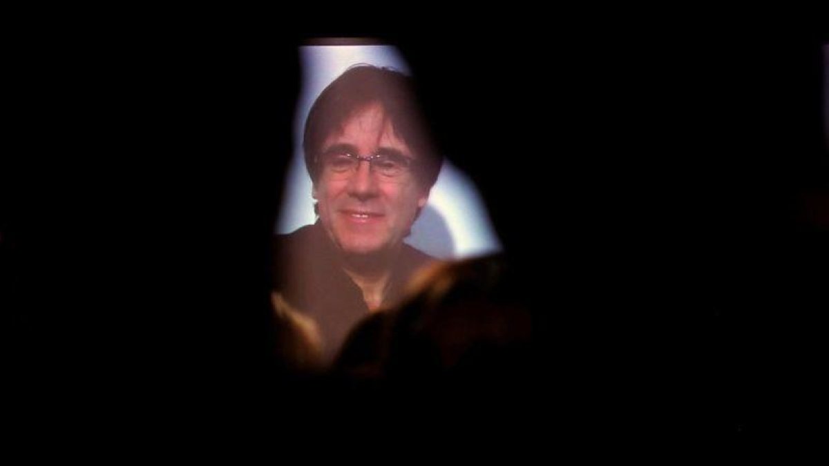 Carles Puigdemont conversa por videoconferencia con candidatos y simpatizantes durante la inauguración de la sede de campaña de Junts per Catalunya.-ALBERTO ESTEVEZ (EFE)