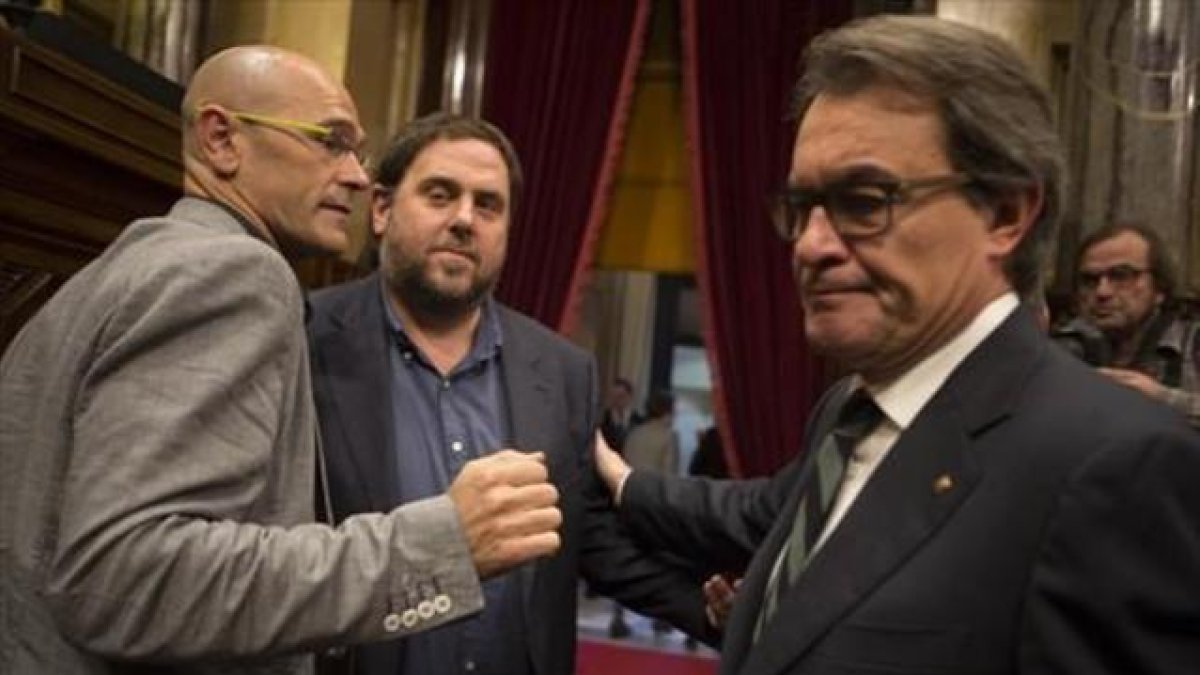 Raül Romeva, Oriol Junqueras y Artur Mas se saludan al terminar la sesión matinal del Parlament de ayer.-ALBERT BERTRAN