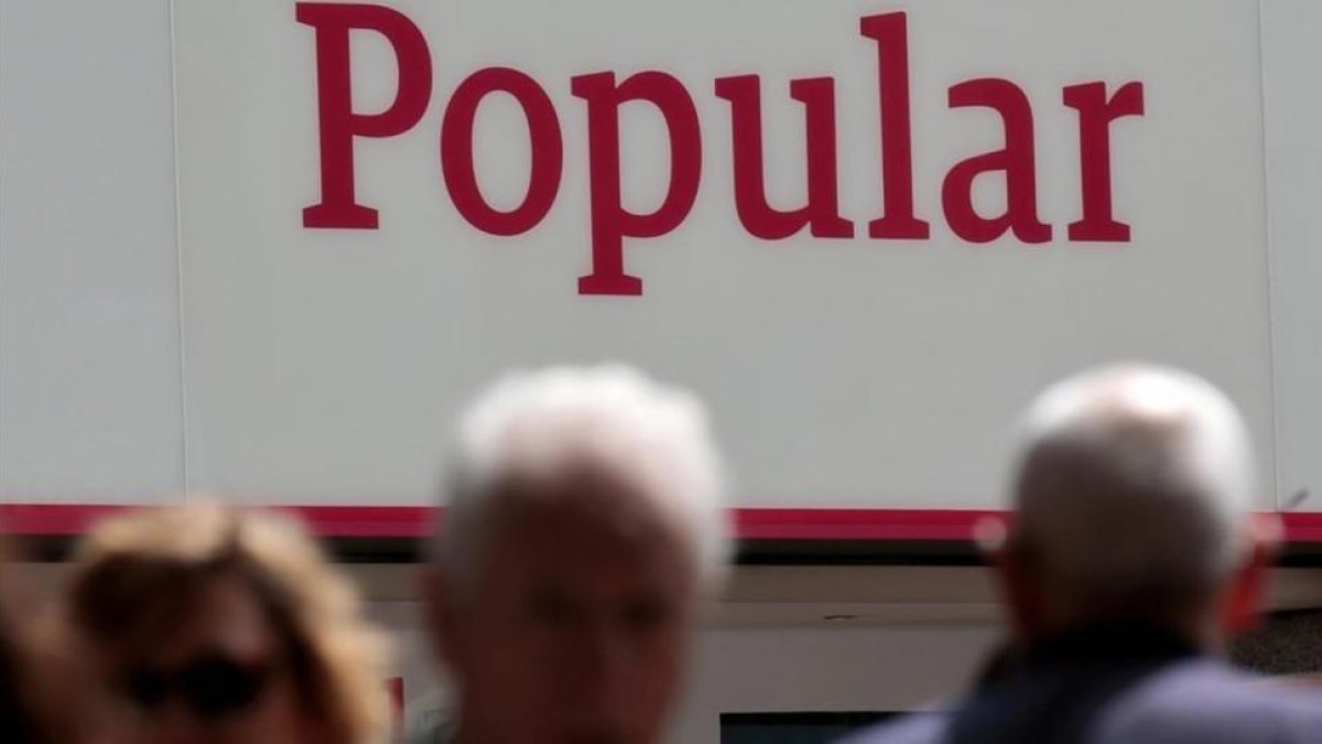 Personas caminando por delante de una oficina del Banco Popular en Madrid.-ANDREA COMAS