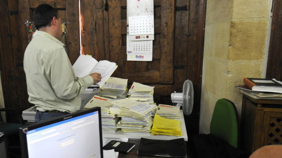 Un empleado de Justicia mira un expediente, delante de numerosos expedientes apilados.-VALENTÍN GUISANDE