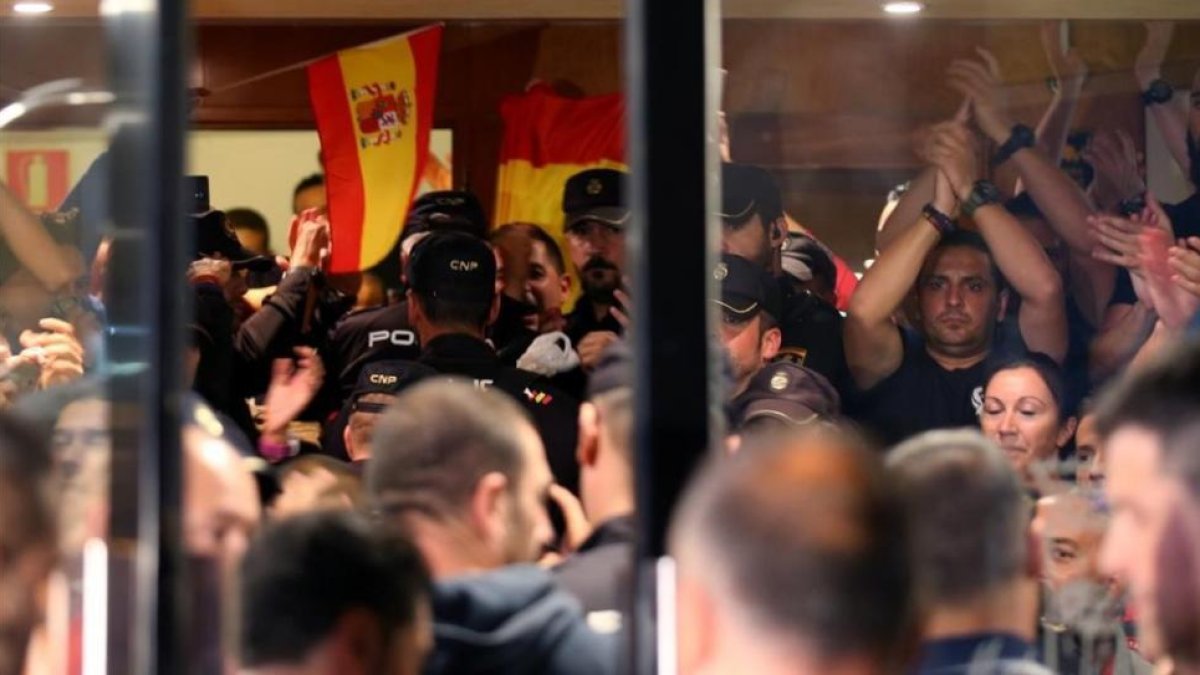 Policías nacionales, en la entrada del hotel de Pineda en el que están alojados, se enfrentan a los ciudadanos que protestan fuera.-ALBERT GEA (REUTERS)