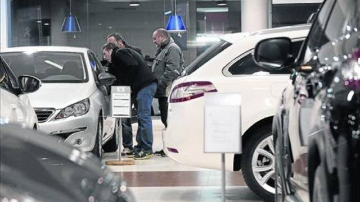 Clientes de un concesionario muestran interés por un modelo a la venta.-Foto: JULIO CARBÓ