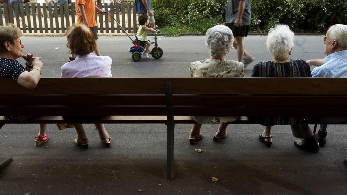 Un grupo de ancianos descansan en un banco en un parque de Barcelona.-JULIO CARBÓ