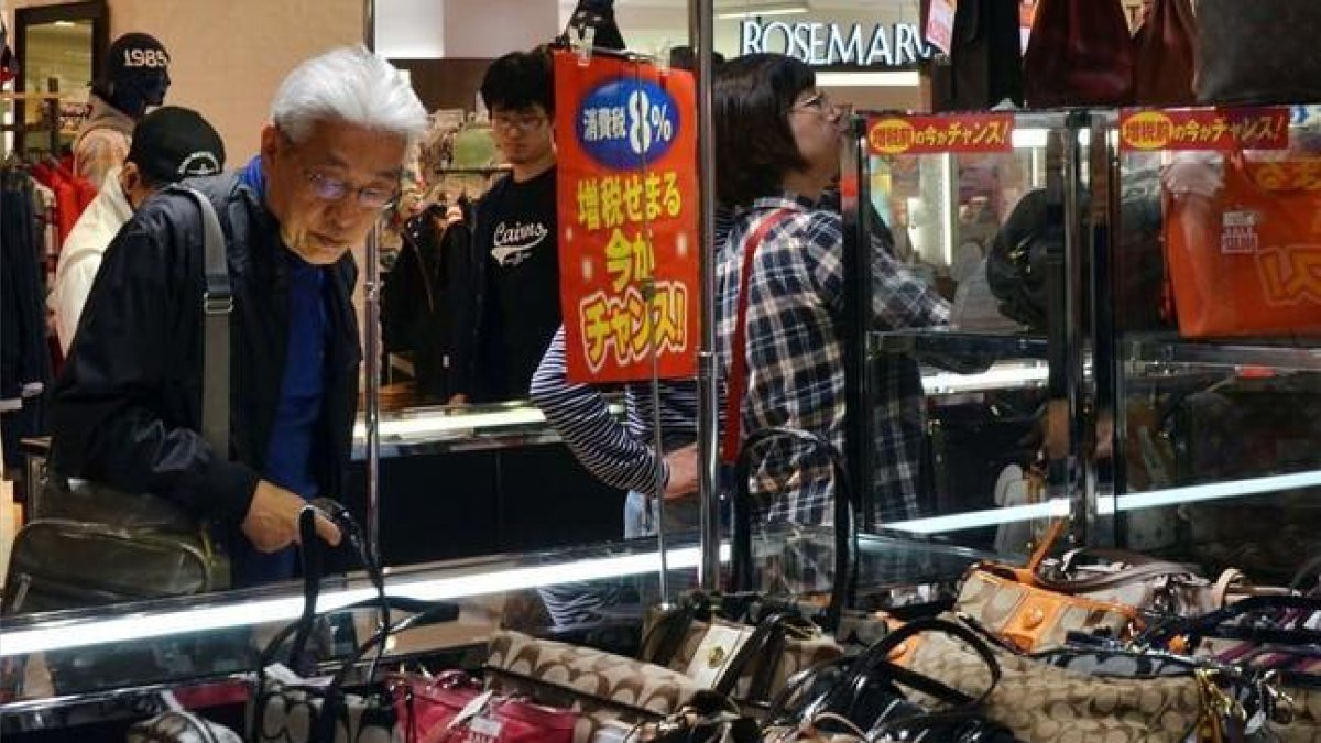 Un ciudadano japonés mira bolsos en una tienda en Tokio.-AFP / YOSHIKAZU TSUNO