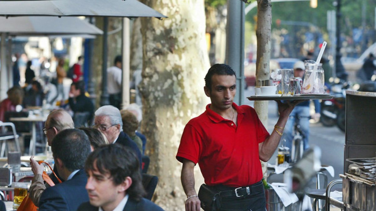 Un camarero trabajando en una terraza de un bar.-RICARD CUGAT (EL PERIÓDICO)