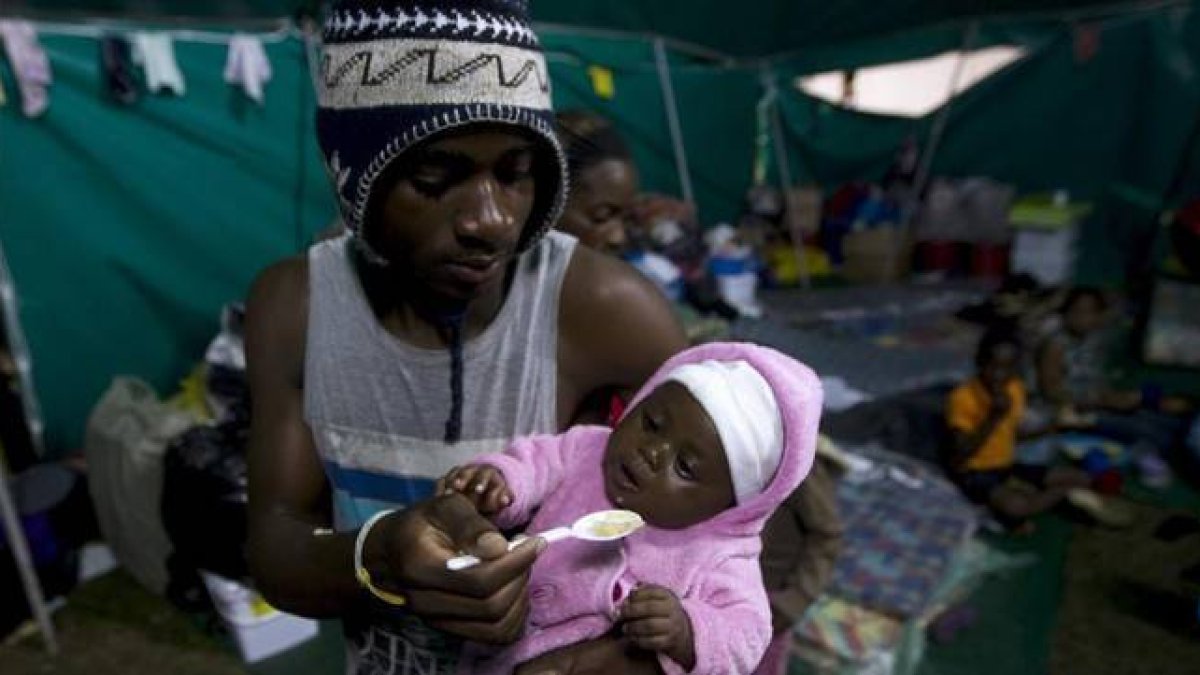 Un extranjero alimenta a su bebé en una tienda donde han sido realojados en Isibingo, en el sur de Durban, este lunes.-Foto:   REUTERS / ROGAN WARD