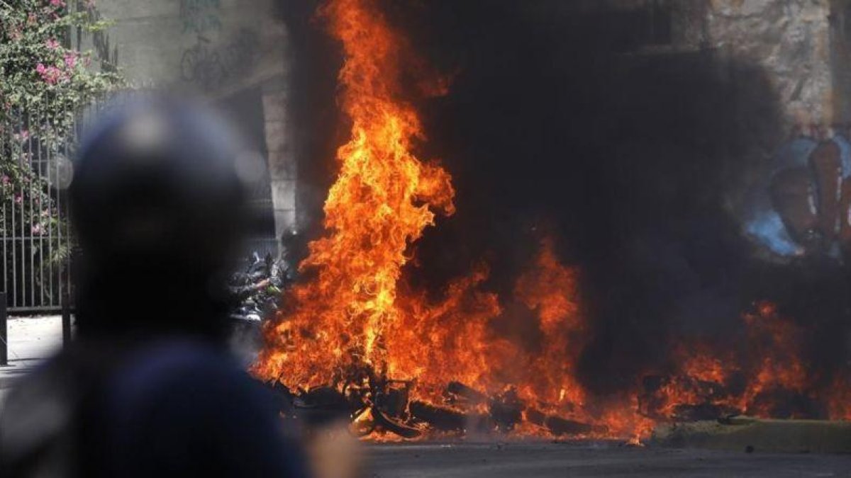 Varios vehículos en llamas tras enfrentamientos entre manifestantes y policías en Venezuela.-CARLOS GARCIA RAWLINS / REUTERS