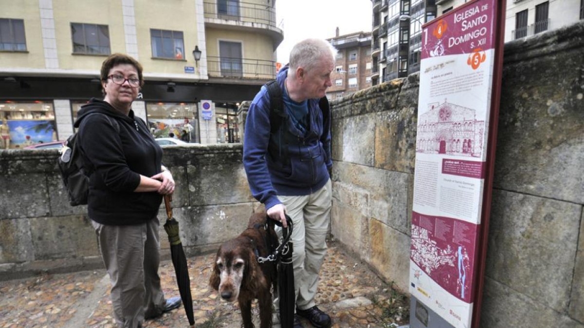 Una pareja de turistas y su perro se detienen a informarse sobre la iglesia de Santo Domingo.-VALENTÍN GUISANDE