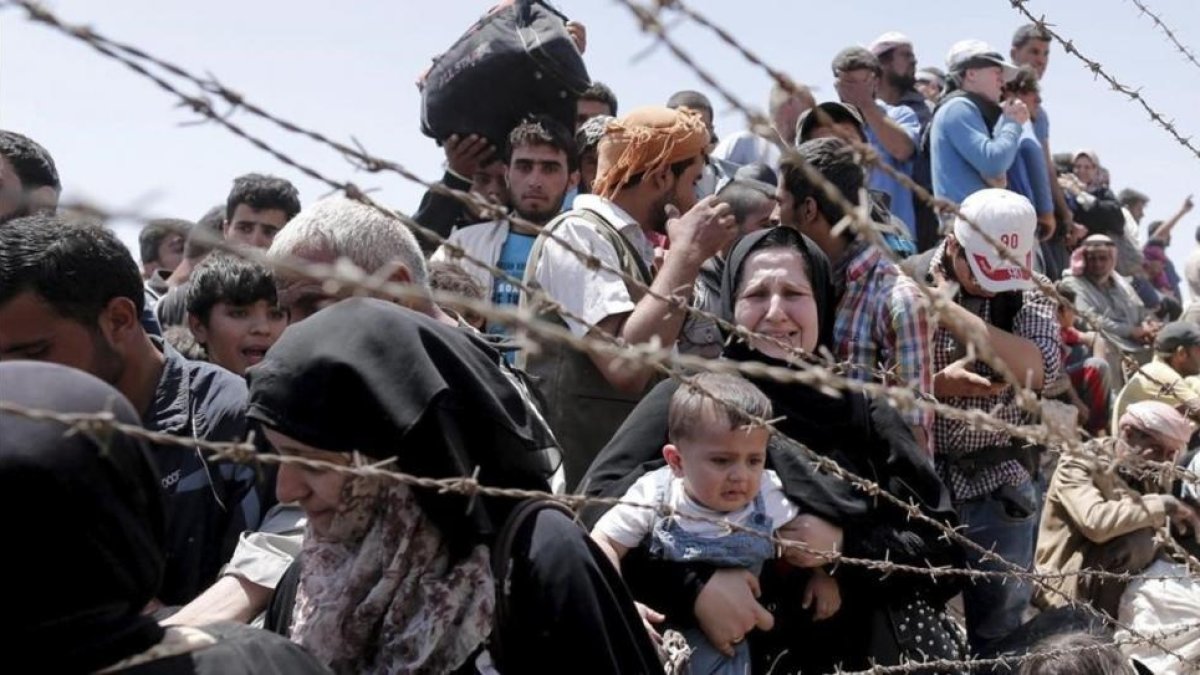 Refugiados sirios esperan cruzar desde su país la frontera que les separa de Turquía cerca de Akcakale en la provincia de Sanliurfa.-EFE / SEDAT SUNA