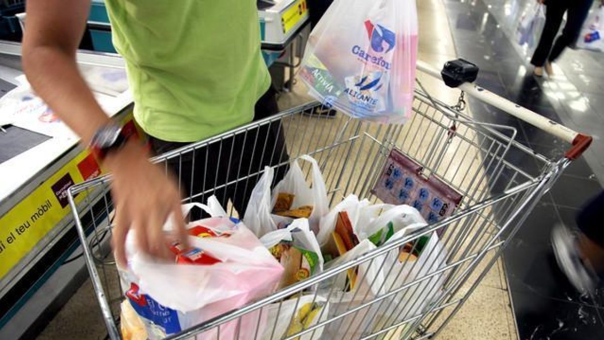 Un cliente llena el carrito de la compra en una gran superficie.-