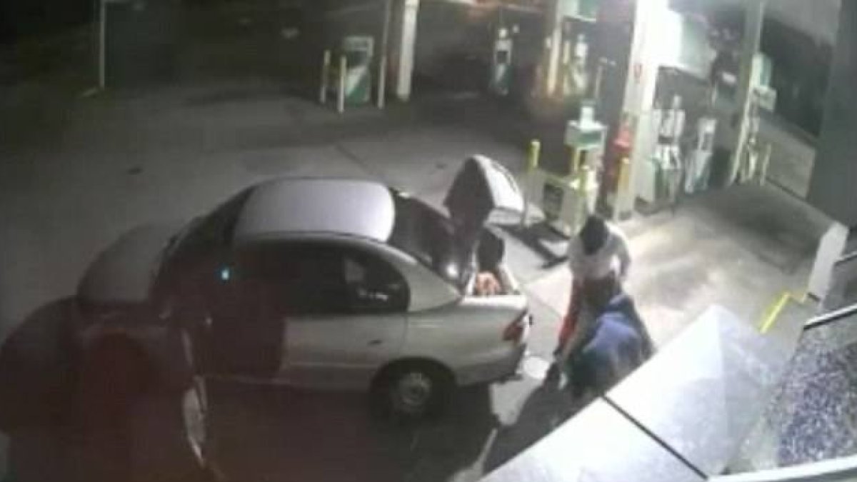 Imagen de la grabación de una cámara de seguridad en que se ve como unos ladrones intentan llevarse un gran botín de tabaco en un saco tan grande que no les cabe en el coche.-