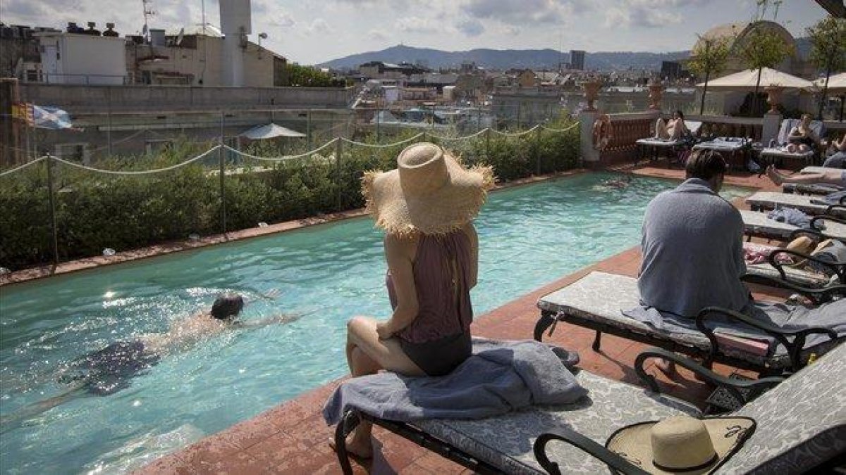 Clientes en la piscina situada en la azotea del Hotel Palace, en Barcelona.-FERRAN NADEU