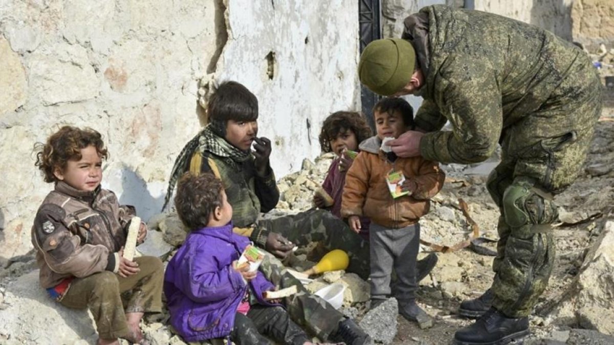 Un soldado ruso atiende a unos niños sirios en Aleppo, Siria.-