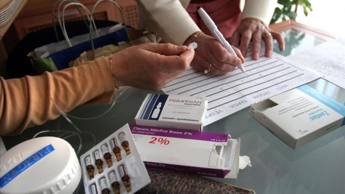 Dos enfermeras preparando los medicamentos para muerte digna en casa de un paciente.-MARC VILA