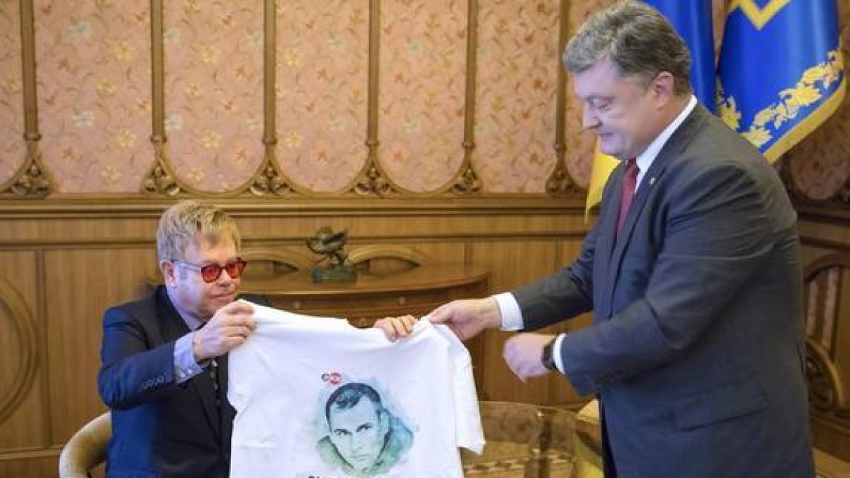 El presidente ucraniano, Petro Poroshenko, entrega una camiseta con la imagen de un cineasta encarcelado en Rusia al cantante Elton John.-EFE / MIKHAIL PALINCHAK