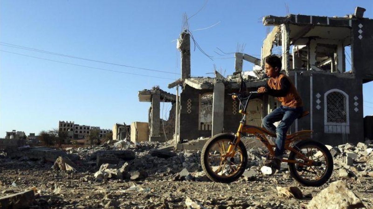 Un niño yemení pasea con su bicicleta junto a los escombros de una vivenda en Saná destrozada por los bombardeos aéreos.-YAHYA ARHAB (EFE)