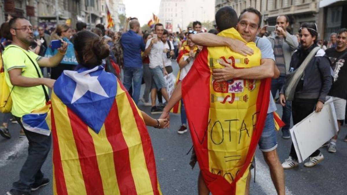 En la imagen una pareja con estelada y bandera española es abrazada por un independentista en Ronda Universitat.-JULIO CARBO